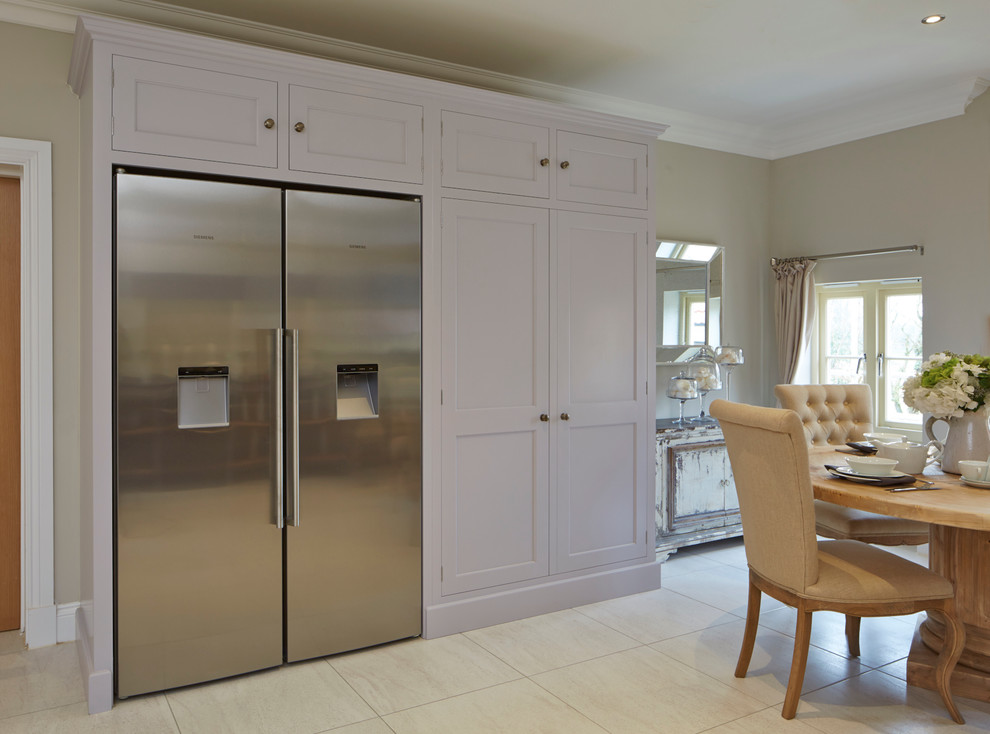 This is an example of a large traditional eat-in kitchen in Wiltshire with beaded inset cabinets, stainless steel appliances, porcelain floors and with island.