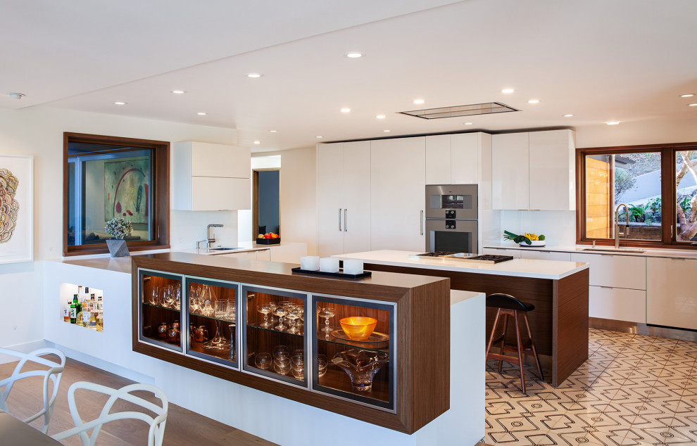 Photo of a large midcentury u-shaped open plan kitchen in San Francisco with an undermount sink, flat-panel cabinets, white cabinets, quartzite benchtops, panelled appliances, cement tiles, with island, multi-coloured floor and white benchtop.