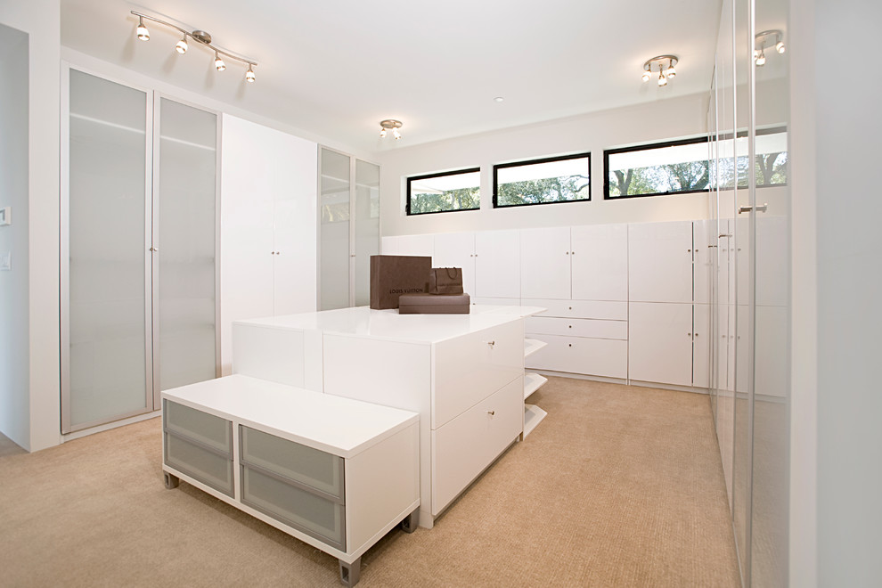 This is an example of a large contemporary gender-neutral dressing room in San Francisco with glass-front cabinets, white cabinets and carpet.