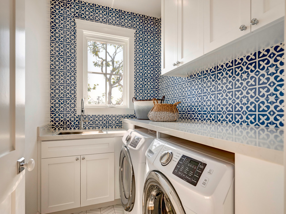 This is an example of a beach style l-shaped dedicated laundry room in Los Angeles with an undermount sink, shaker cabinets, white cabinets, white walls, a side-by-side washer and dryer, white floor and white benchtop.