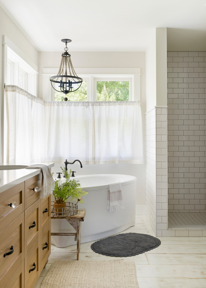 This is an example of a large modern master bathroom in Minneapolis with beaded inset cabinets, light wood cabinets, a freestanding tub, an open shower, a one-piece toilet, beige walls, painted wood floors, a drop-in sink, white floor, an open shower and white benchtops.