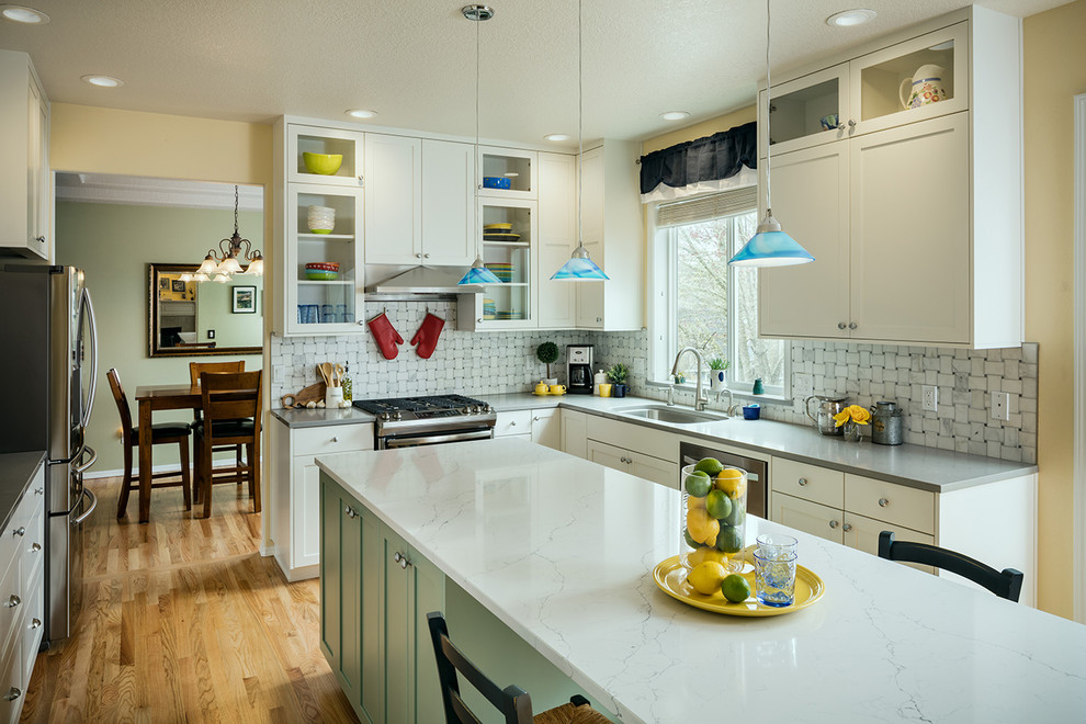Transitional medium tone wood floor eat-in kitchen photo with an undermount sink, shaker cabinets, white cabinets, quartzite countertops, gray backsplash, stainless steel appliances, an island and gray countertops