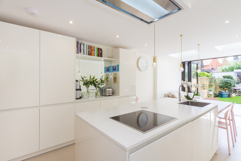 Contemporary kitchen in London with an undermount sink, flat-panel cabinets, white cabinets, mirror splashback and with island.