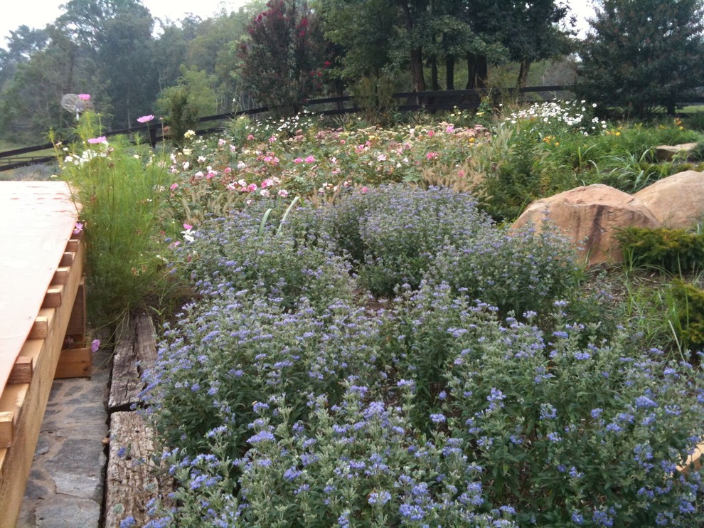 This is an example of a large rustic partial sun backyard stone formal garden for summer.