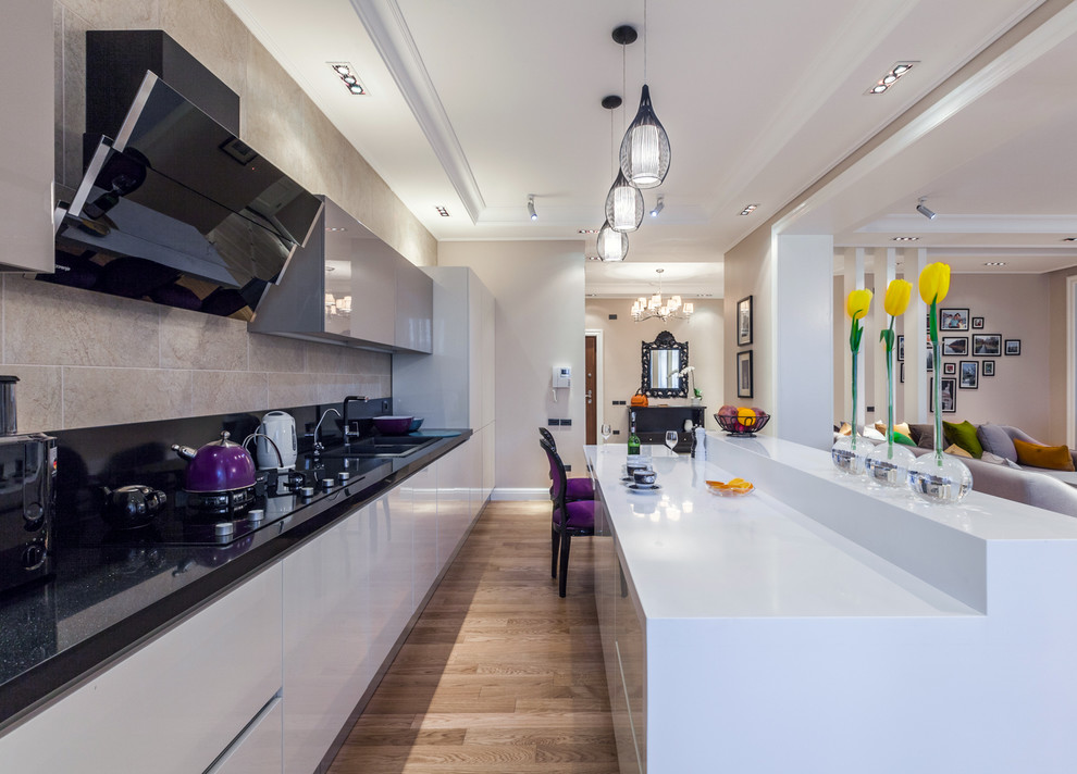 Photo of a large eclectic eat-in kitchen in Other with flat-panel cabinets, white cabinets, limestone benchtops, black splashback, ceramic splashback, light hardwood floors and with island.