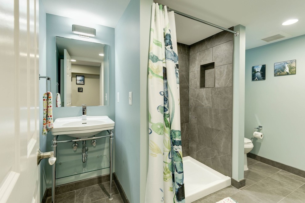 This is an example of a mid-sized transitional 3/4 bathroom in DC Metro with an alcove shower, a two-piece toilet, gray tile, stone tile, blue walls, marble floors, a console sink, solid surface benchtops, grey floor and a shower curtain.