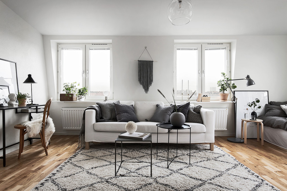 This is an example of a mid-sized scandinavian formal open concept living room in Stockholm with white walls, light hardwood floors and no fireplace.