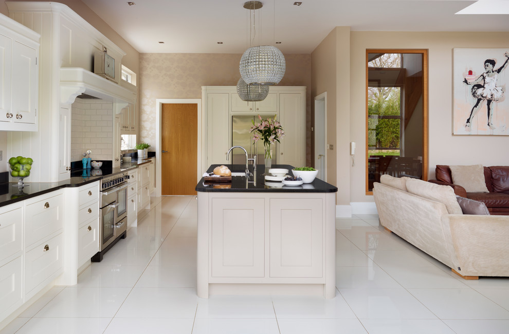 Design ideas for a large traditional single-wall open plan kitchen in London with shaker cabinets, beige cabinets, granite worktops, beige splashback, metro tiled splashback, stainless steel appliances and an island.