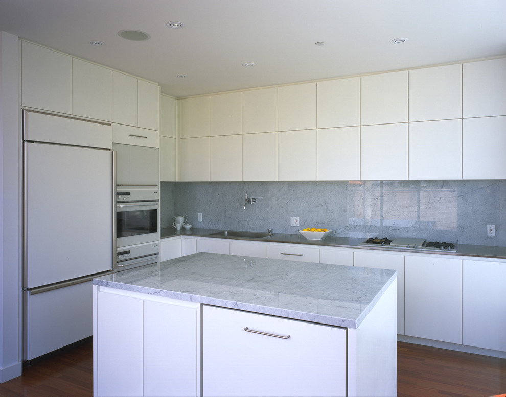 This is an example of a modern kitchen in San Francisco with flat-panel cabinets, white cabinets, grey splashback and panelled appliances.