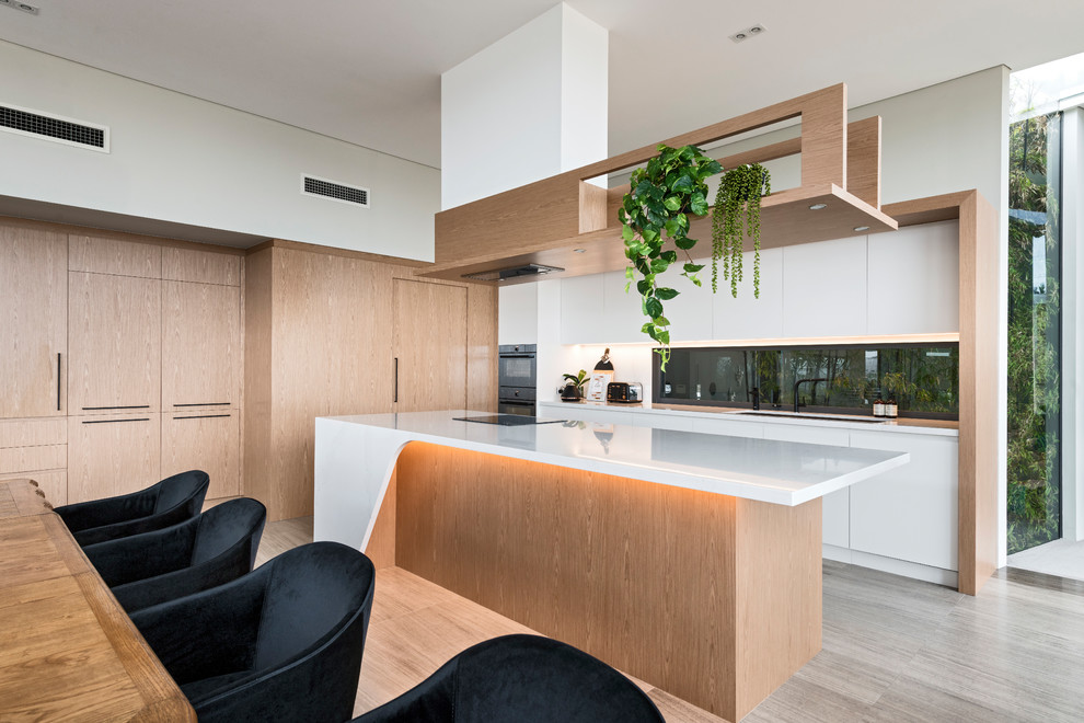 Inspiration for a large modern l-shaped eat-in kitchen in Perth with an undermount sink, light wood cabinets, solid surface benchtops, black appliances, porcelain floors, with island, grey floor, white benchtop, flat-panel cabinets and window splashback.