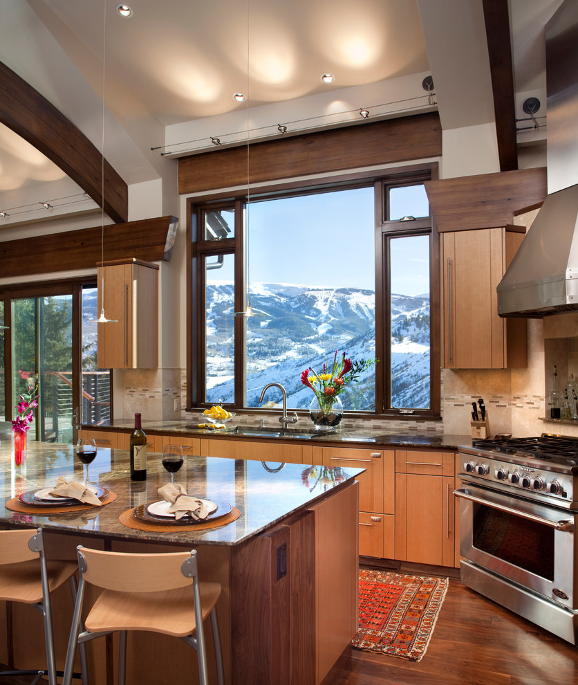 This is an example of a mid-sized contemporary l-shaped eat-in kitchen in Denver with stainless steel appliances, an undermount sink, flat-panel cabinets, medium wood cabinets, granite benchtops, beige splashback, ceramic splashback, medium hardwood floors, with island and brown benchtop.