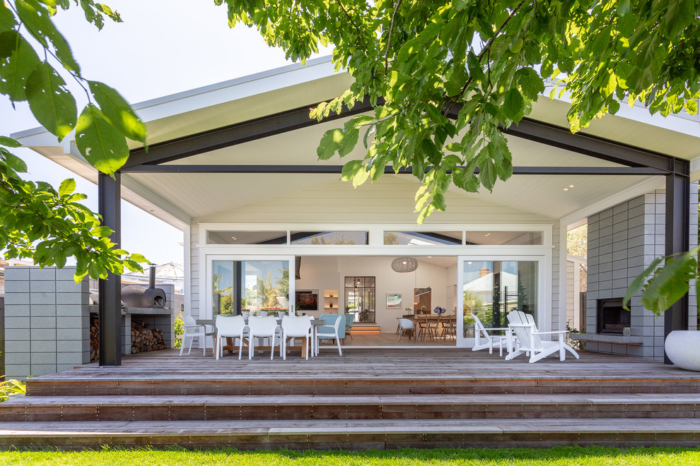 Inspiration for a large transitional backyard deck in Auckland with with fireplace and a roof extension.