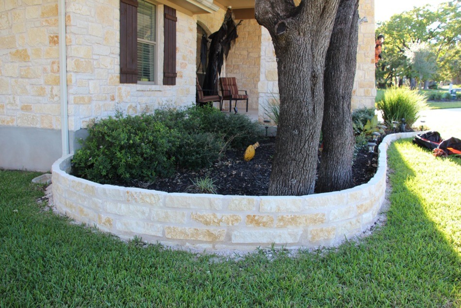 Design ideas for a large traditional front yard partial sun garden in Austin with a retaining wall and natural stone pavers.
