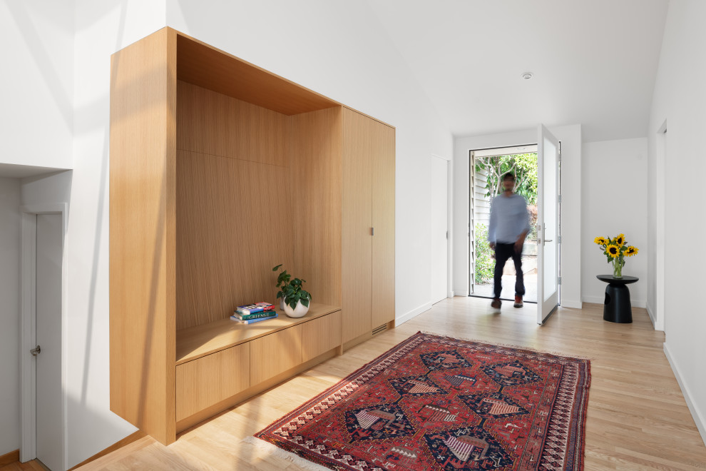 Idee per un grande ingresso o corridoio moderno con pareti bianche, pavimento in legno massello medio e soffitto a volta