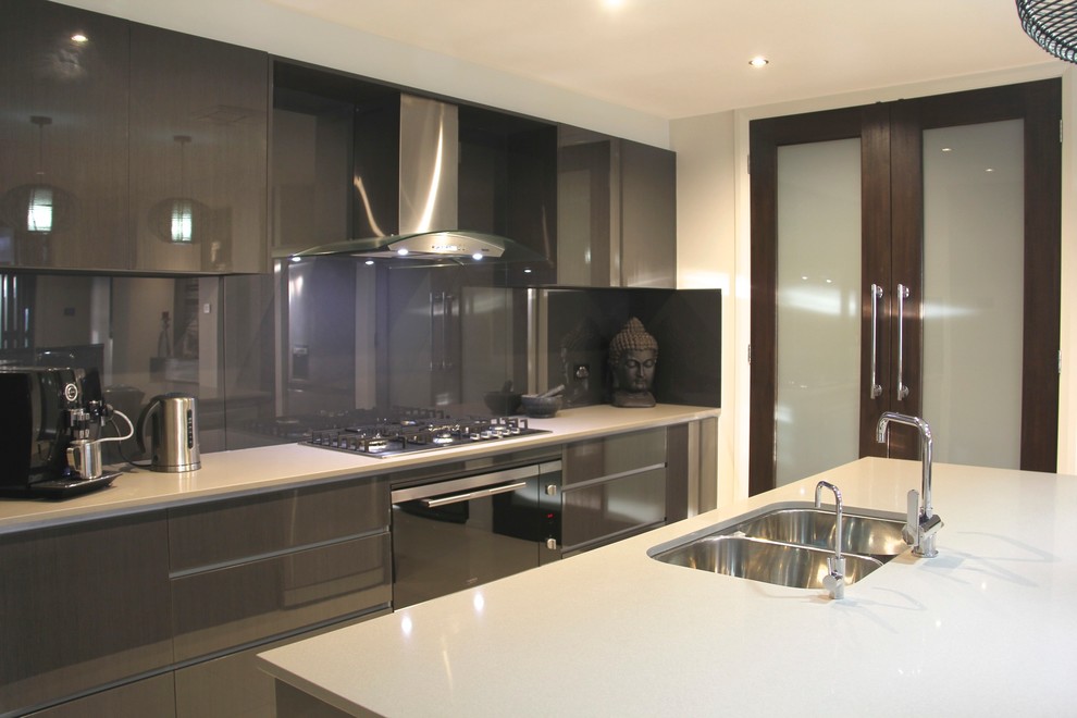 Inspiration for a mid-sized asian eat-in kitchen in Sydney with a drop-in sink, flat-panel cabinets, grey cabinets, grey splashback, glass sheet splashback, stainless steel appliances, porcelain floors, with island and granite benchtops.