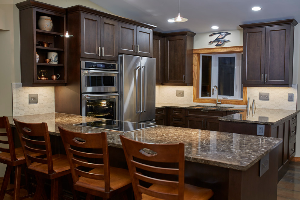 Mid-sized transitional u-shaped porcelain tile eat-in kitchen photo with an undermount sink, shaker cabinets, dark wood cabinets, quartz countertops, beige backsplash, stone tile backsplash, stainless steel appliances and a peninsula
