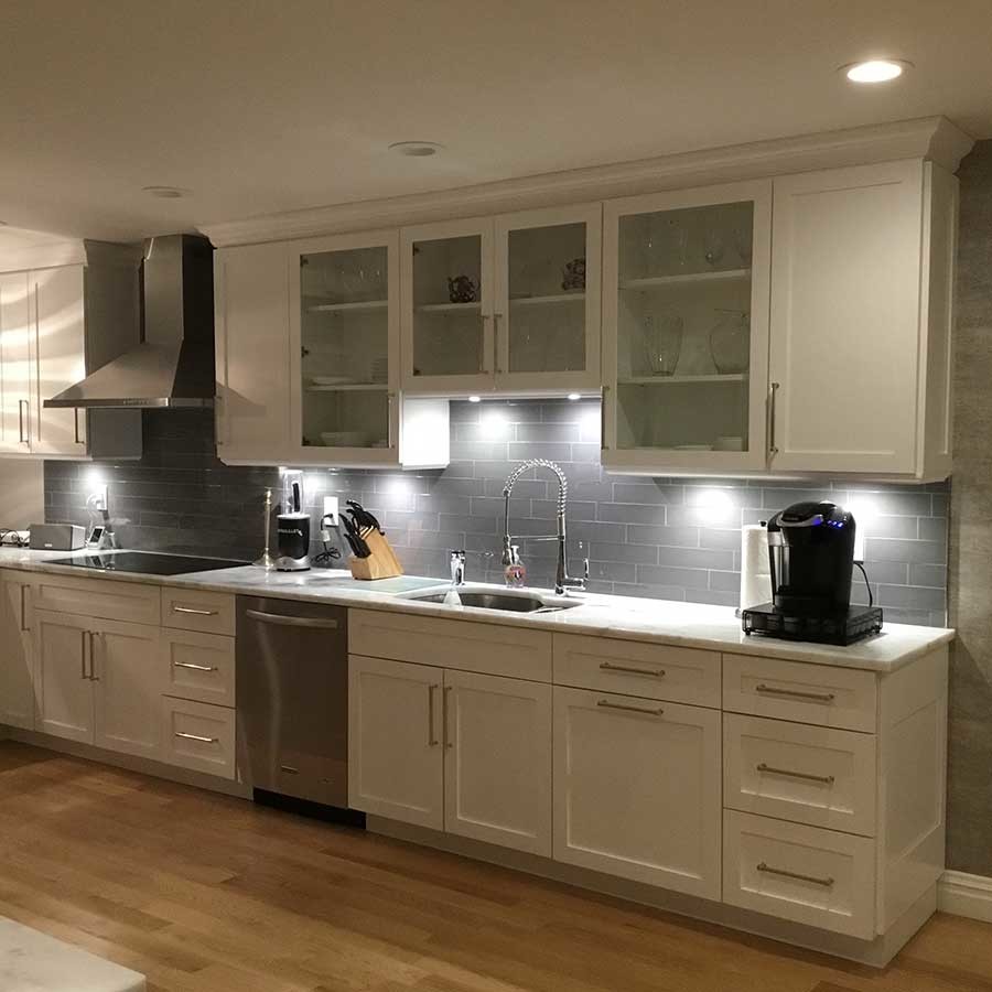 Mid-sized transitional u-shaped separate kitchen in New York with shaker cabinets, white cabinets, marble benchtops, grey splashback, marble splashback, stainless steel appliances, light hardwood floors, with island and brown floor.