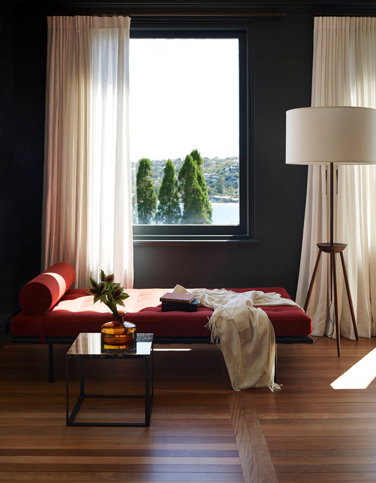 This is an example of a contemporary formal living room in Sydney with black walls and medium hardwood floors.