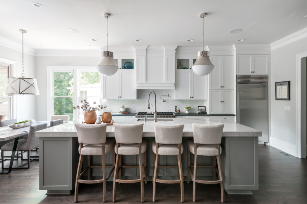This is an example of a large transitional galley eat-in kitchen in Atlanta with a single-bowl sink, shaker cabinets, white cabinets, quartzite benchtops, white splashback, stainless steel appliances, with island, brown floor, dark hardwood floors and black benchtop.