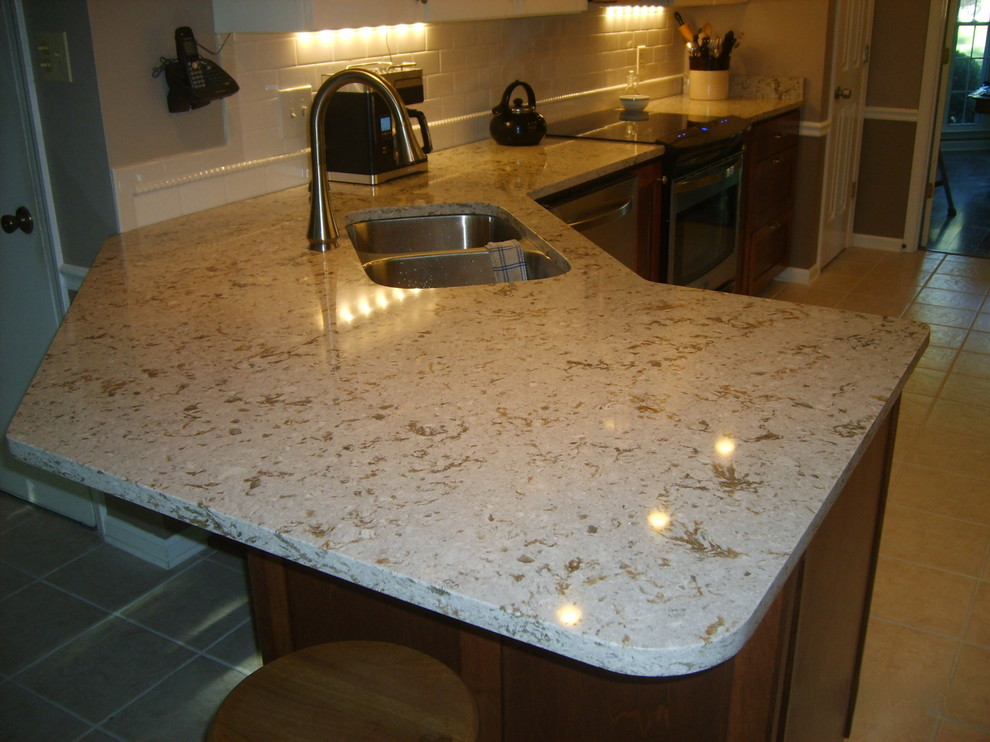 Example of a transitional galley eat-in kitchen design with an undermount sink, shaker cabinets, dark wood cabinets, quartz countertops, white backsplash, subway tile backsplash and stainless steel appliances