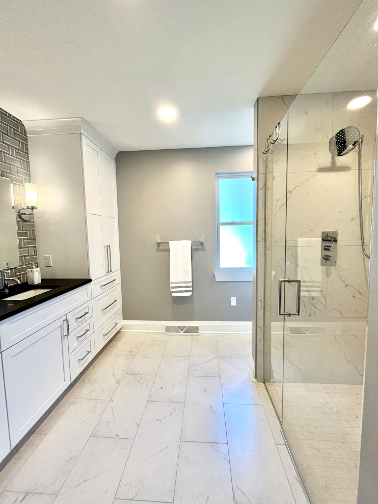 Walk-in shower - mid-sized transitional master gray tile and stone tile porcelain tile, white floor and double-sink walk-in shower idea with shaker cabinets, white cabinets, a two-piece toilet, gray walls, an undermount sink, granite countertops, a hinged shower door, black countertops and a built-in vanity