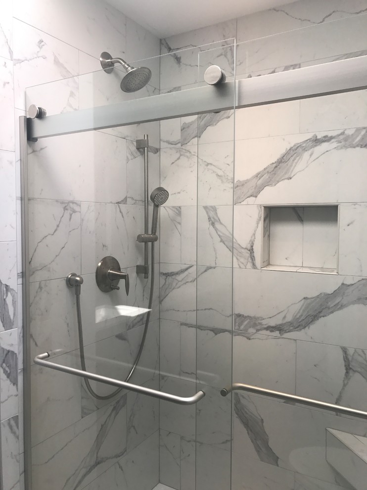 Photo of a mid-sized transitional master bathroom in Milwaukee with flat-panel cabinets, dark wood cabinets, an alcove shower, a two-piece toilet, white tile, porcelain tile, grey walls, laminate floors, an integrated sink, solid surface benchtops, grey floor and a sliding shower screen.