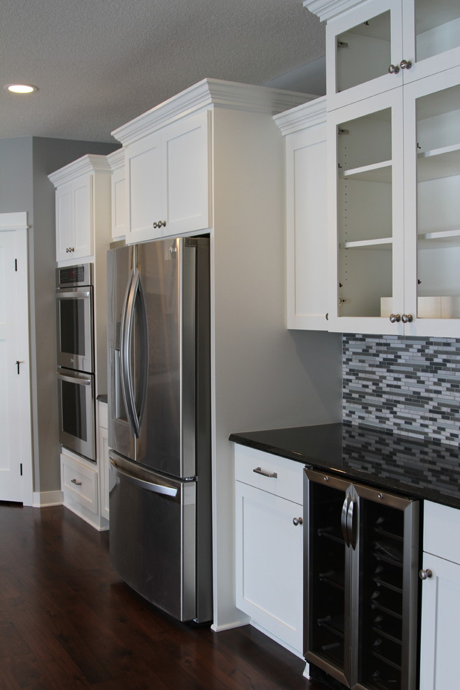 Eat-in kitchen - eat-in kitchen idea in Minneapolis with an undermount sink, flat-panel cabinets, white cabinets, granite countertops, glass sheet backsplash and stainless steel appliances