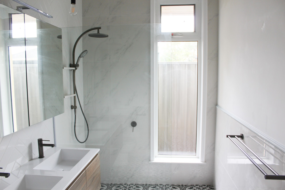 Design ideas for a large traditional 3/4 bathroom in Perth with flat-panel cabinets, medium wood cabinets, an open shower, a one-piece toilet, white tile, subway tile, white walls, mosaic tile floors, an integrated sink, solid surface benchtops, black floor, an open shower and white benchtops.
