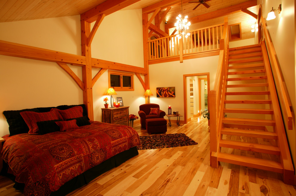 Design ideas for a large country loft-style bedroom in Calgary with beige walls and light hardwood floors.