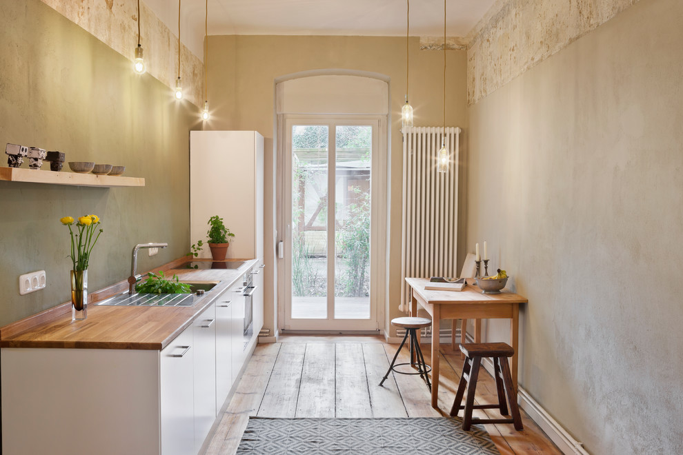 Inspiration for a small traditional single-wall separate kitchen in Berlin with an integrated sink, wood benchtops, green splashback, no island, flat-panel cabinets, white cabinets and medium hardwood floors.