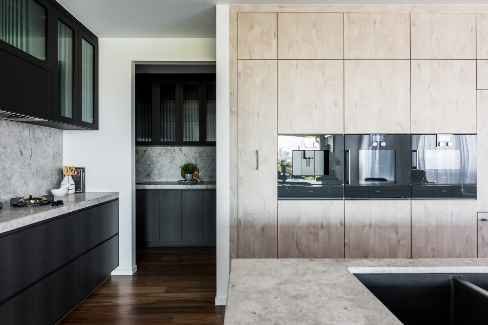 Design ideas for an expansive contemporary kitchen in Brisbane with an undermount sink, flat-panel cabinets, limestone benchtops, limestone splashback, black appliances and with island.