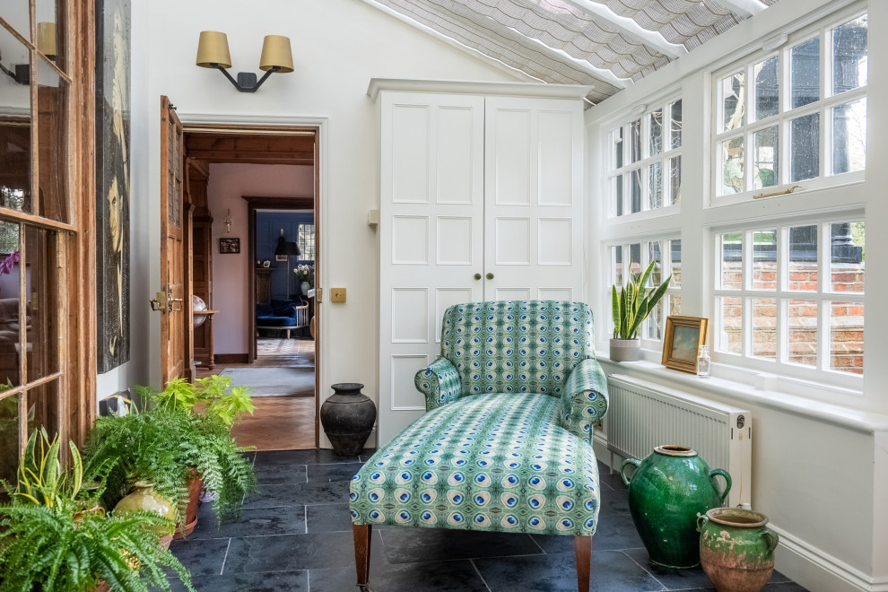 This is an example of a mid-sized eclectic sunroom in London with slate floors, a glass ceiling and black floor.