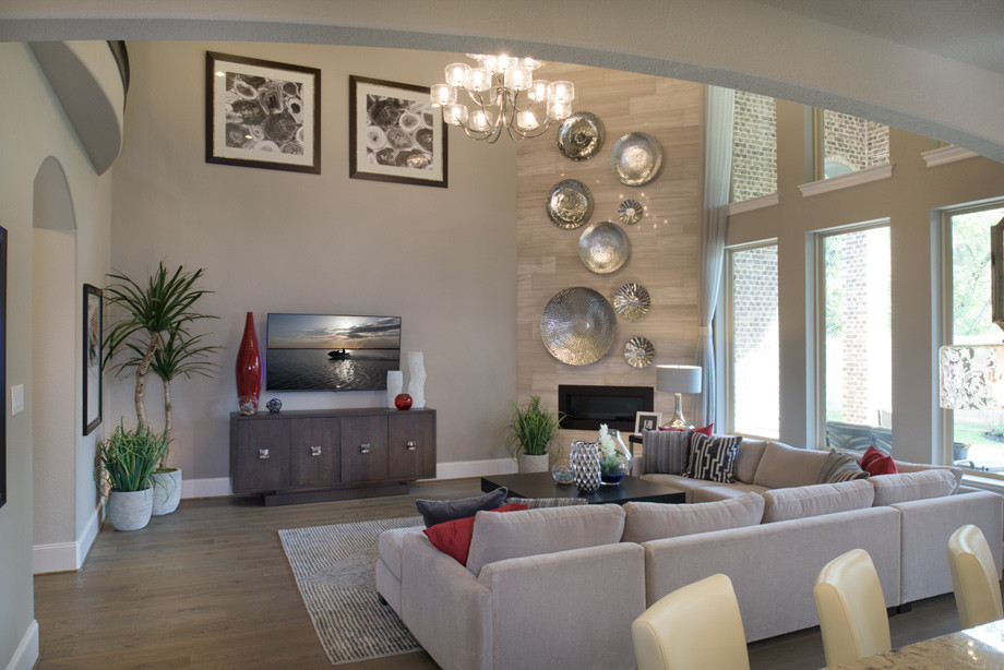 Inspiration for a large transitional open concept family room in Houston with grey walls, light hardwood floors, a corner fireplace, a tile fireplace surround and a wall-mounted tv.