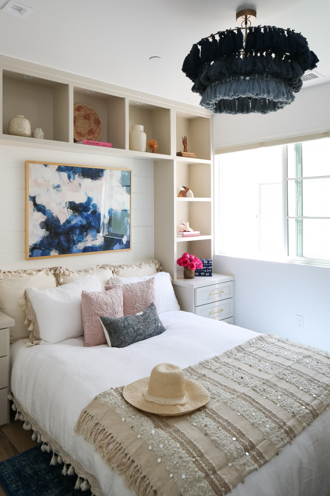 Inspiration for a beach style guest bedroom in Orange County with white walls, medium hardwood floors, no fireplace, brown floor and planked wall panelling.