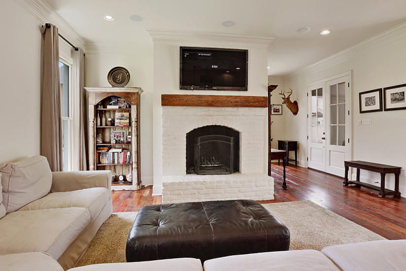 Large transitional open concept family room in New Orleans with white walls, dark hardwood floors, a standard fireplace, a brick fireplace surround and a wall-mounted tv.