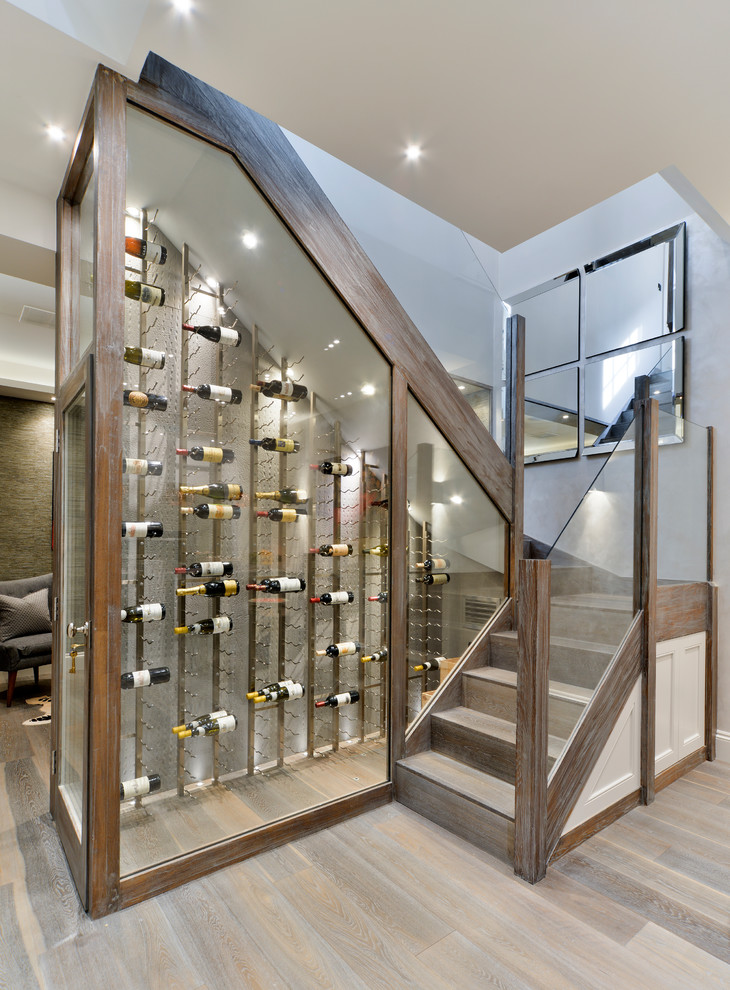 Photo of a small contemporary wine cellar in London with medium hardwood floors and display racks.
