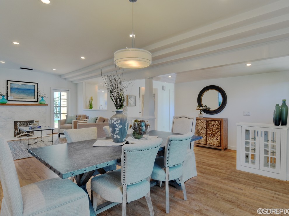 Small beach style open plan dining in San Diego with white walls, light hardwood floors, a standard fireplace and a stone fireplace surround.