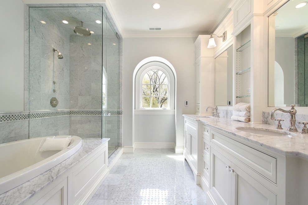 This is an example of a large transitional master bathroom in Atlanta with an undermount sink, beaded inset cabinets, white cabinets, marble benchtops, a drop-in tub, a corner shower, a one-piece toilet, yellow tile, stone tile, grey walls and marble floors.
