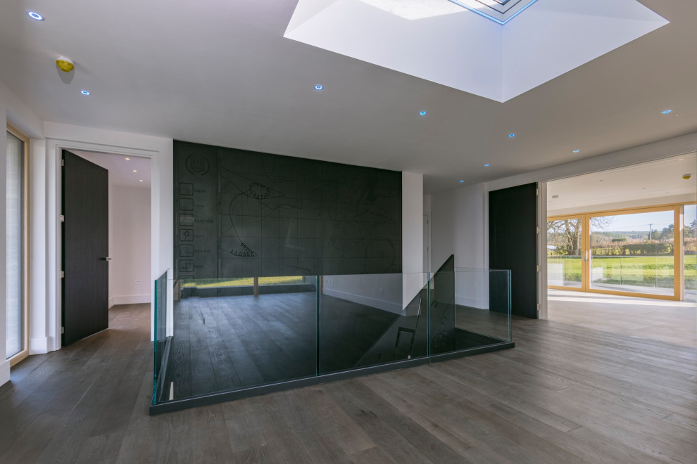Großer Moderner Flur mit schwarzer Wandfarbe, Laminat, braunem Boden und Wandpaneelen in Surrey