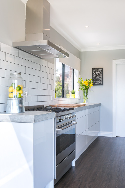 Inspiration for an expansive contemporary galley eat-in kitchen in Melbourne with a double-bowl sink, open cabinets, white cabinets, concrete benchtops, white splashback, subway tile splashback, stainless steel appliances and with island.