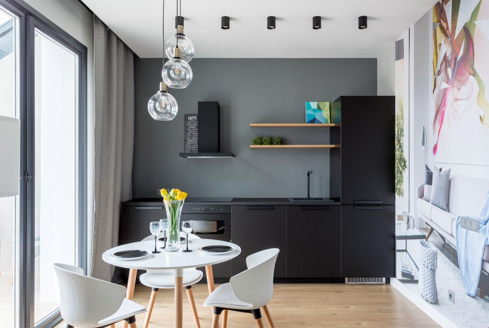 Design ideas for a small contemporary single-wall eat-in kitchen in Saint Petersburg with a drop-in sink, flat-panel cabinets, black cabinets, black appliances, medium hardwood floors, no island, brown floor, black benchtop and grey splashback.