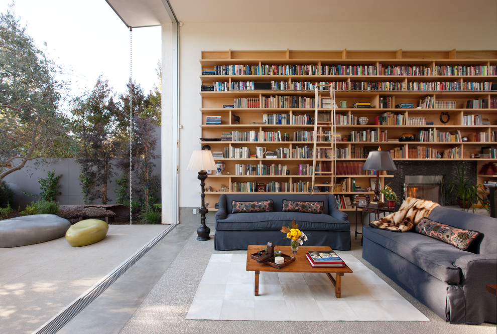Photo of a small modern open concept living room in Los Angeles with a library, white walls, concrete floors, a standard fireplace and a stone fireplace surround.