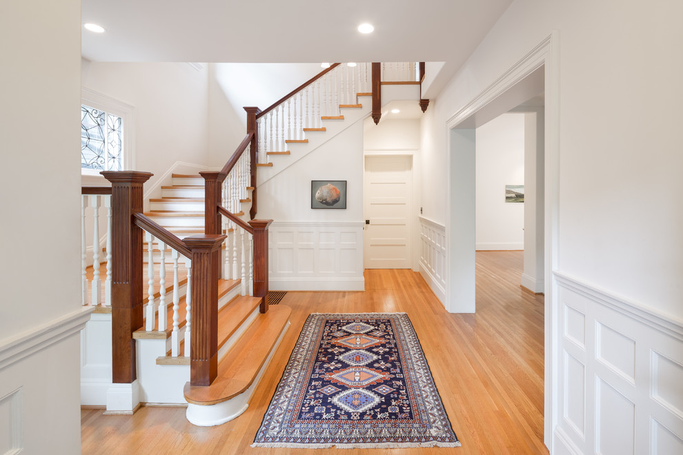 This is an example of a large traditional wood u-shaped staircase in Portland with painted wood risers.