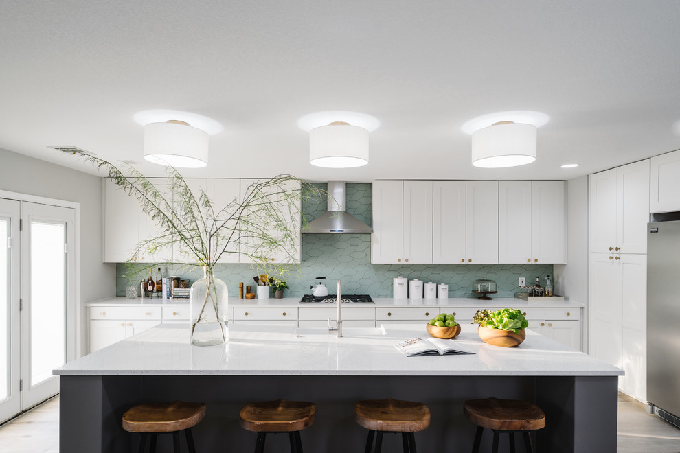 Inspiration for a large modern l-shaped eat-in kitchen in Austin with a farmhouse sink, shaker cabinets, white cabinets, quartz benchtops, green splashback, stone tile splashback, stainless steel appliances, porcelain floors and with island.
