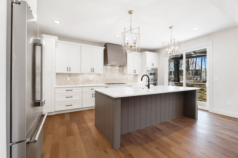 Kitchen - mid-sized transitional l-shaped medium tone wood floor kitchen idea in Cincinnati with an undermount sink, shaker cabinets, white cabinets, quartzite countertops, mosaic tile backsplash, stainless steel appliances, an island and white countertops