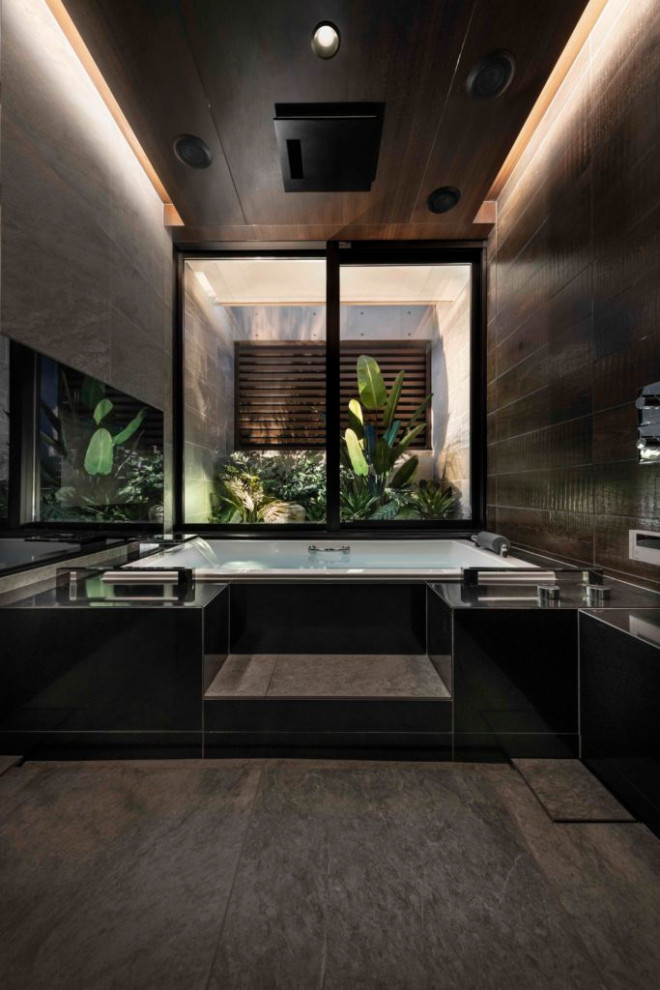 Стильный дизайн: ванная комната в стиле модернизм с накладной ванной, черной плиткой, черными стенами, врезной раковиной, черным полом, тумбой под одну раковину, встроенной тумбой и многоуровневым потолком - последний тренд