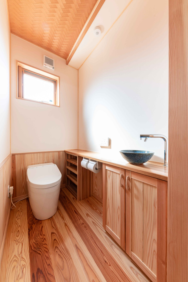 Inspiration for a small cloakroom in Other with freestanding cabinets, brown cabinets, a one-piece toilet, blue tiles, mosaic tiles, white walls, light hardwood flooring, a vessel sink, stainless steel worktops, brown floors, brown worktops, a built in vanity unit, a wallpapered ceiling and wallpapered walls.
