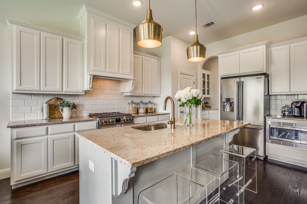 Photo of a country l-shaped kitchen in Dallas with an undermount sink, shaker cabinets, beige cabinets, white splashback, subway tile splashback, stainless steel appliances, dark hardwood floors, with island and beige benchtop.