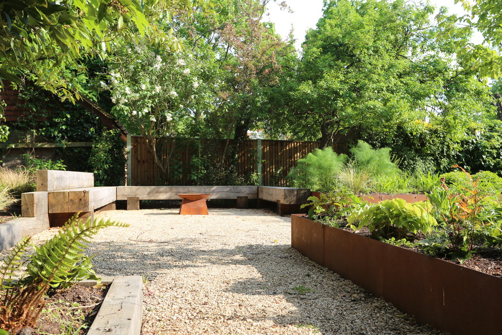 Photo of a mid-sized country backyard formal garden in London with a fire feature and gravel.