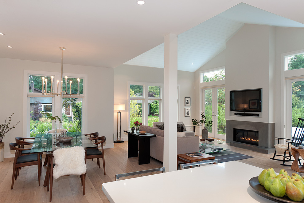 This is an example of a contemporary open concept family room in Vancouver with a ribbon fireplace, a wall-mounted tv and light hardwood floors.